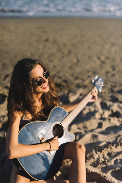 Mujer sentada en la arena con guitarra