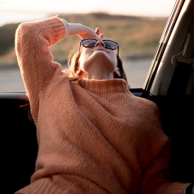 Mujer sentada en el auto y con gafas de sol