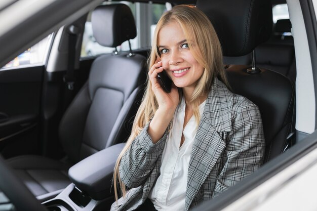 Mujer sentada en el auto mientras habla por teléfono