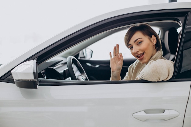 Mujer sentada en un auto en una sala de exposición de autos