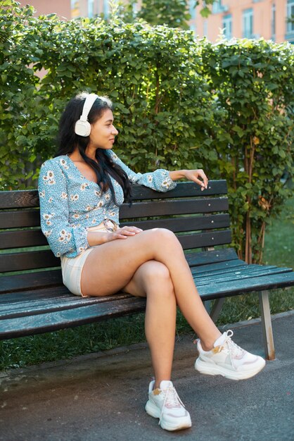 Mujer sentada en un banco y escuchando música