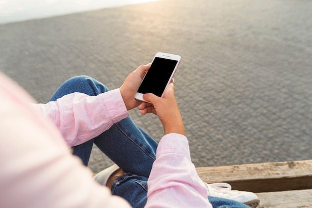 Mujer sentada en el banco con teléfono móvil