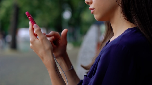 Mujer sentada en el banquillo y con smartphone. Vista cercana