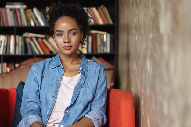 Foto gratuita mujer sentada en una biblioteca en un sofá