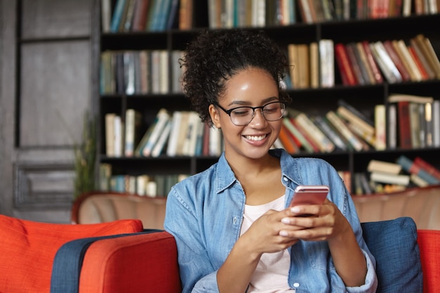 Mujer sentada en una biblioteca con su teléfono