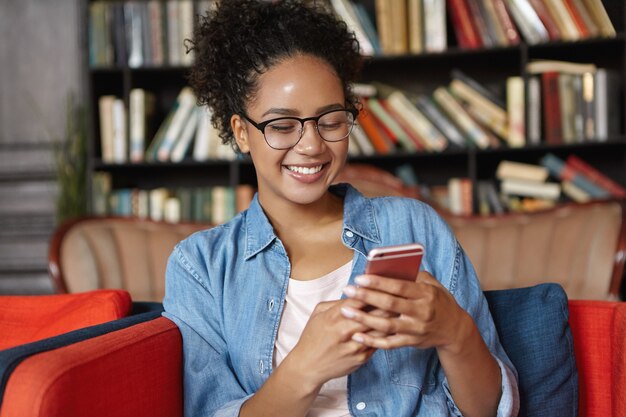 Mujer sentada en una biblioteca con su teléfono