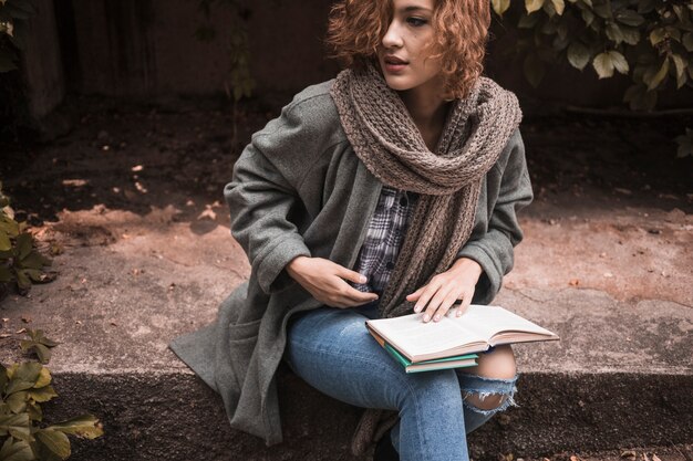 Mujer sentada a bordo y sosteniendo el libro abierto