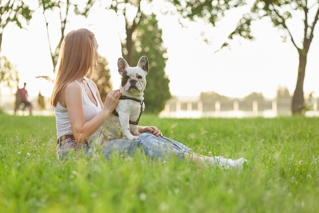 Mujer sentada con bulldog francés sobre césped