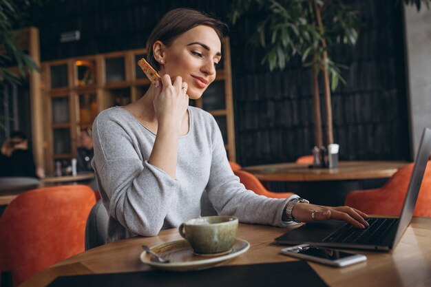 Mujer sentada en un café tomando café y trabajando en una computadora