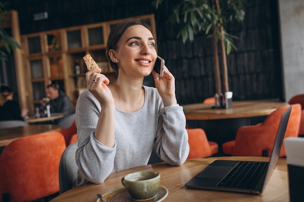 Mujer sentada en un café tomando café y trabajando en una computadora