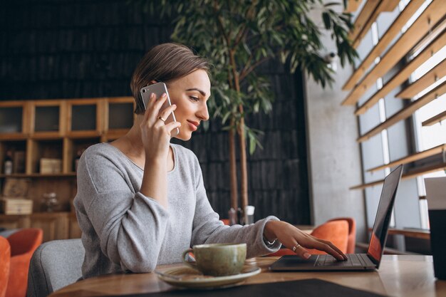 Mujer sentada en un café tomando café y trabajando en una computadora