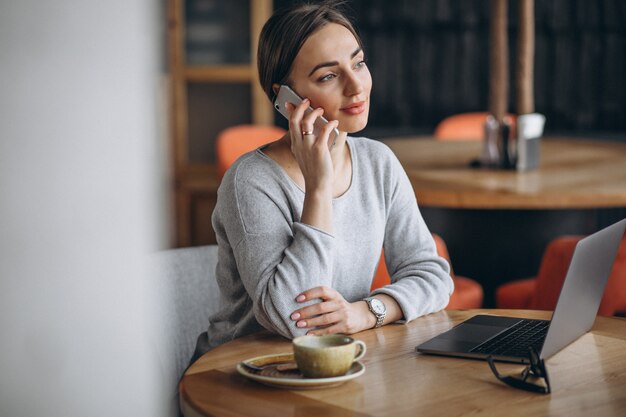 Mujer sentada en un café tomando café y trabajando en una computadora