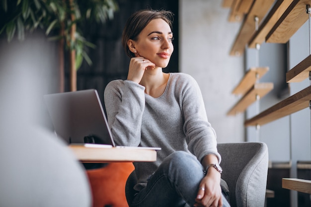 Mujer sentada en un café tomando café y trabajando en una computadora