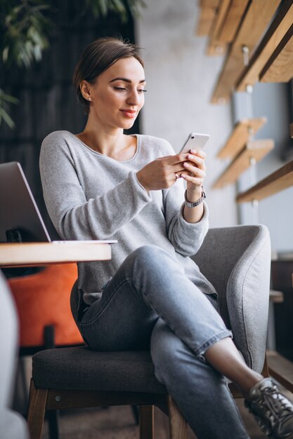 Mujer sentada en un café tomando café y trabajando en una computadora