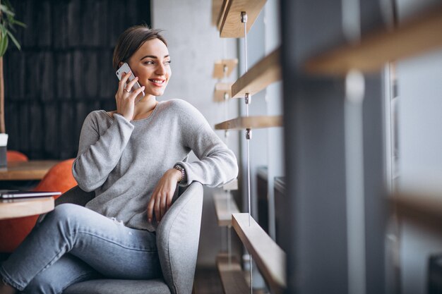 Mujer sentada en un café tomando café y trabajando en una computadora