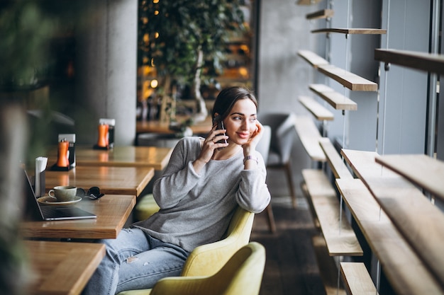 Mujer sentada en un café tomando café y trabajando en una computadora