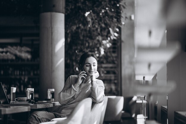 Mujer sentada en un café tomando café y trabajando en una computadora