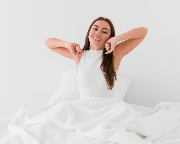 Mujer sentada en la cama por la mañana