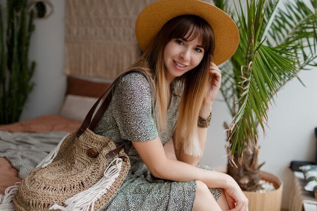 Mujer sentada en la cama en su apartamento boho