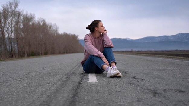 Mujer sentada en la carretera de tiro completo