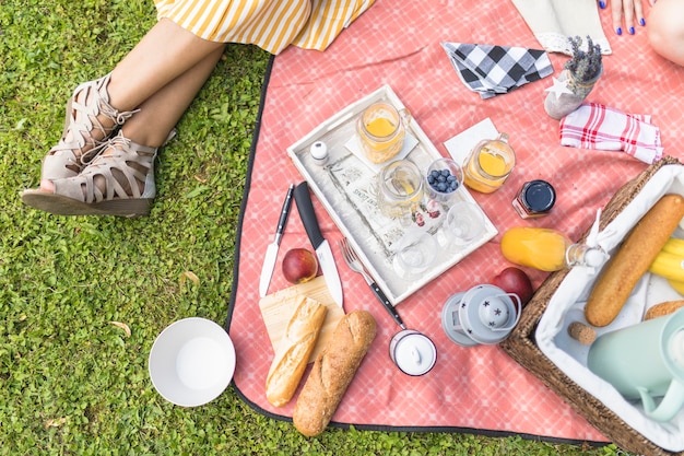 Mujer sentada cerca de la merienda en manta en picnic