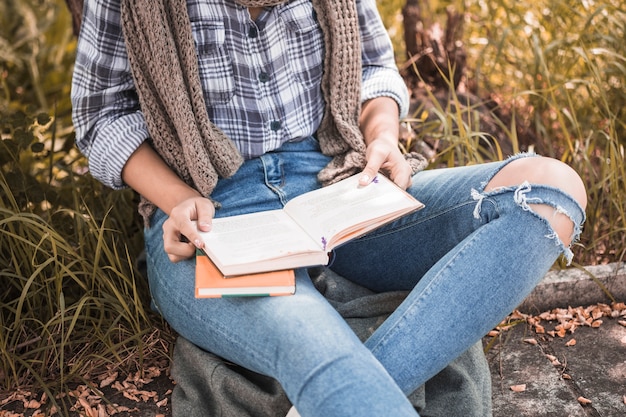 Foto gratuita mujer sentada en el césped y sosteniendo el libro abierto