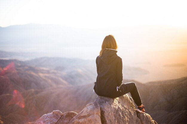Una mujer sentada en la cima de una montaña