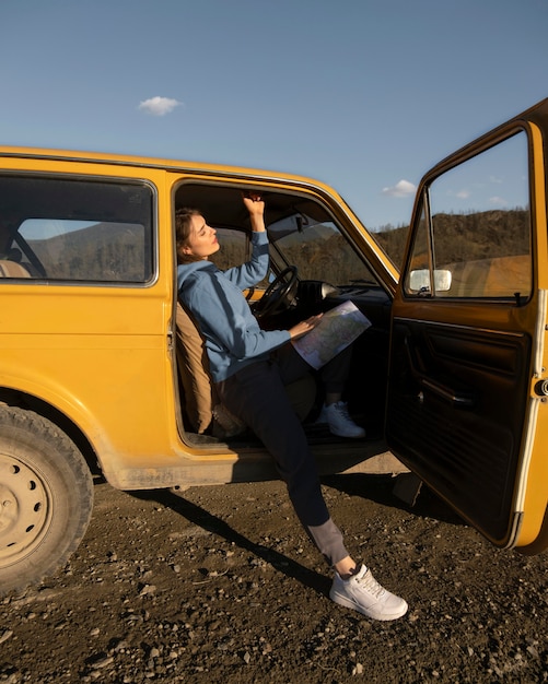 Mujer sentada en el coche con mapa de tiro completo