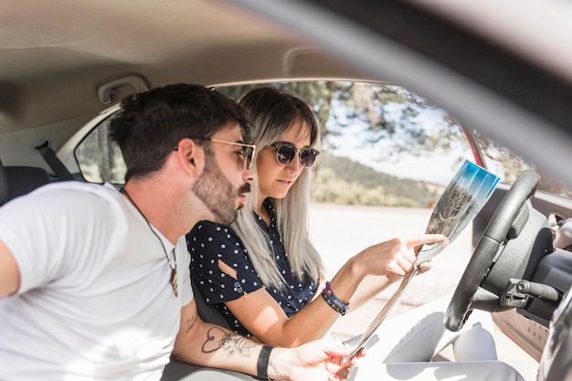 Mujer sentada en el coche que muestra el destino en el mapa a su novio
