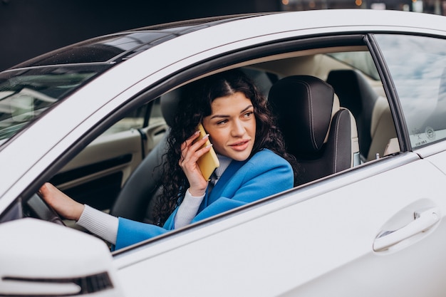 Mujer sentada en el coche y mediante teléfono móvil