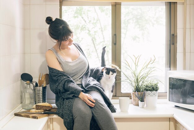 Mujer sentada en la cocina con su gato