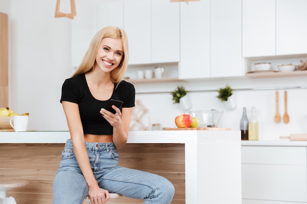 Mujer sentada en la cocina con teléfono