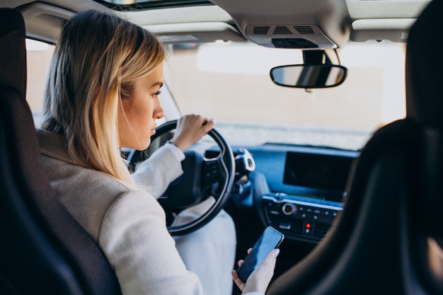 Mujer sentada dentro del auto eléctrico mientras carga