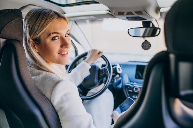 Mujer sentada dentro del auto eléctrico mientras carga