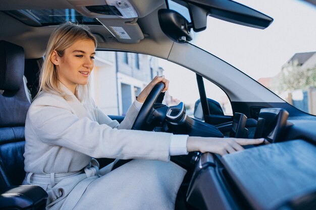 Mujer sentada dentro del auto eléctrico mientras carga