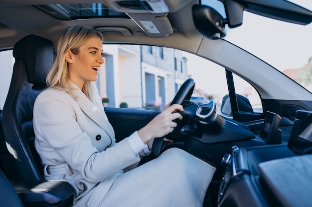 Mujer sentada dentro del auto eléctrico mientras carga