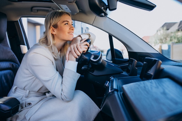 Mujer sentada dentro del auto eléctrico mientras carga