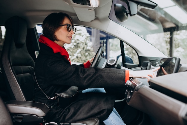 Mujer sentada dentro del auto eléctrico mientras lo carga