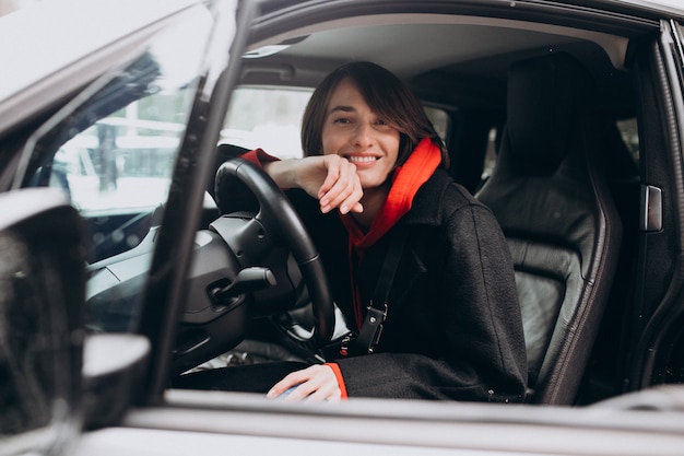 Mujer sentada dentro del auto eléctrico mientras lo carga