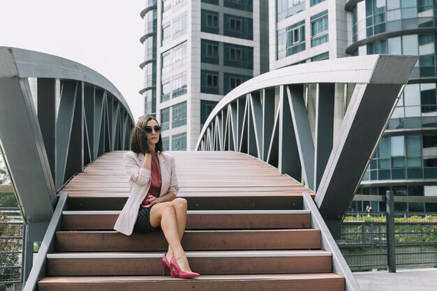 Mujer sentada en la escalera hablando por celular