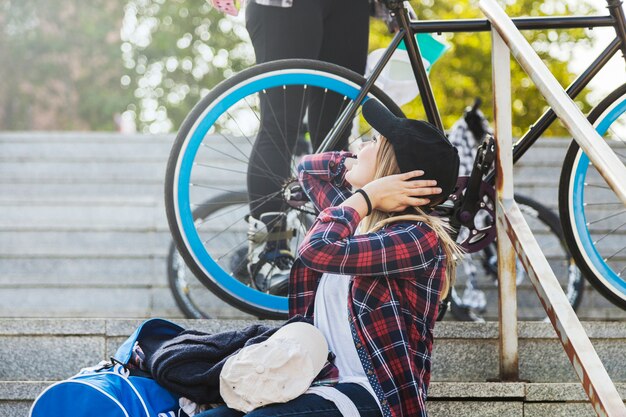 Mujer sentada en las escaleras cerca de la bicicleta