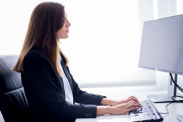 Mujer sentada escribiendo en un ordenador