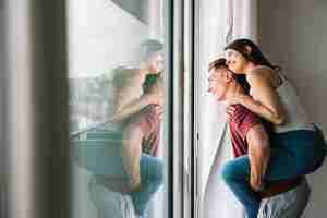 Foto gratuita mujer sentada en la espalda del hombre y mirando a la ventana