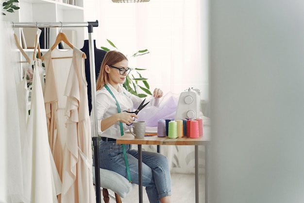 Mujer sentada en estudio y coser tela