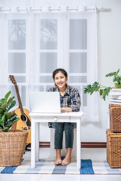 Una mujer sentada felizmente con una computadora portátil en la mesa.