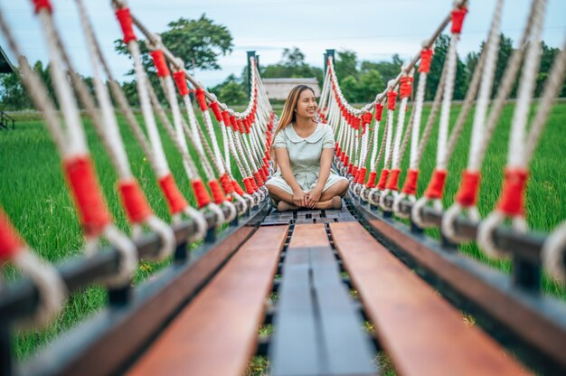 Mujer sentada felizmente en un puente de madera