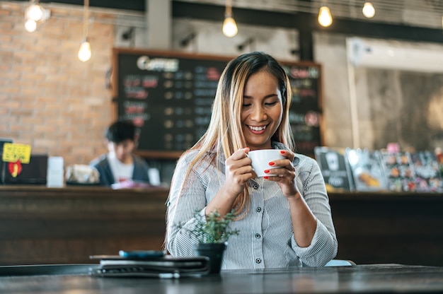 Mujer sentada felizmente tomando café en la cafetería