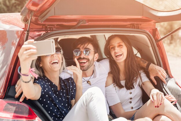 Mujer sentada en la fotografía de toma de tronco de coche a través de teléfono móvil