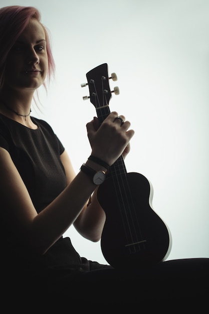 Foto gratuita mujer sentada con una guitarra en la escuela de música