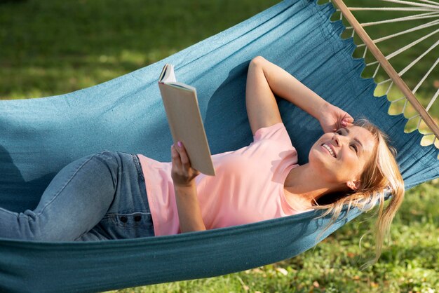 Mujer sentada en una hamaca y sosteniendo un libro vista alta